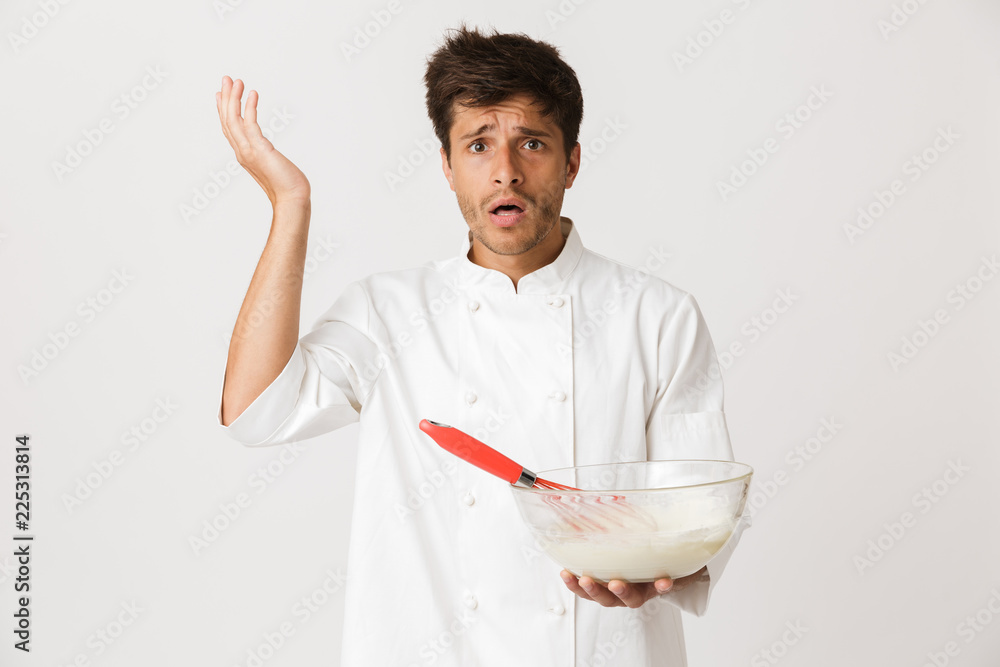 Confused shocked young chef isolated over white background cooking. Confused shocked young chef isolated over white background cooking.
