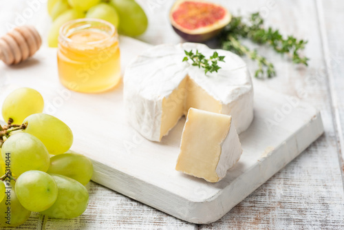 Cheese plate with brie, camembert, honey and fruits, close up view, selective focus. Gourmet appetizer plate