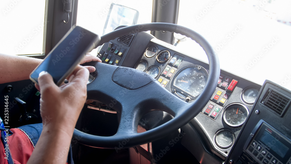 Closeup image of truck driver using smartphone while driving. Danger in transport. Irresponsible driver