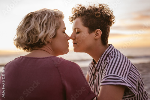 Affectionate young lesbian couple enjoying a romantic beach sunset together
