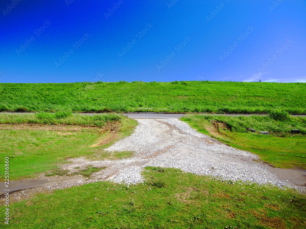 秋の河川敷の砂利道と土手風景