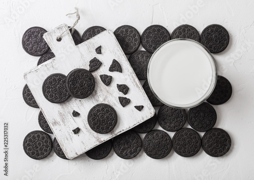Sandwich black cookie consisting of two chocolate wafers with cream filling with glass of milk on stone background.