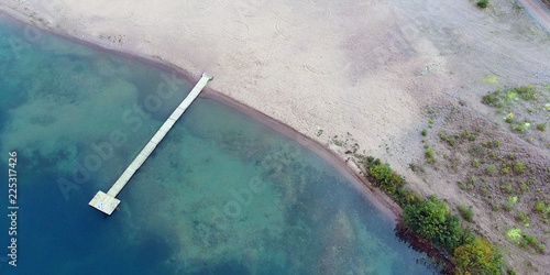Aerial panorama view of sandy beach with long wooden pier.