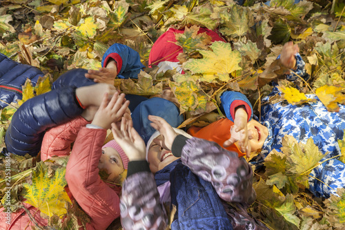 Golden Autumn, group of children lie on their backs in yellow leaves, Happy children in autumn park lying on leaves