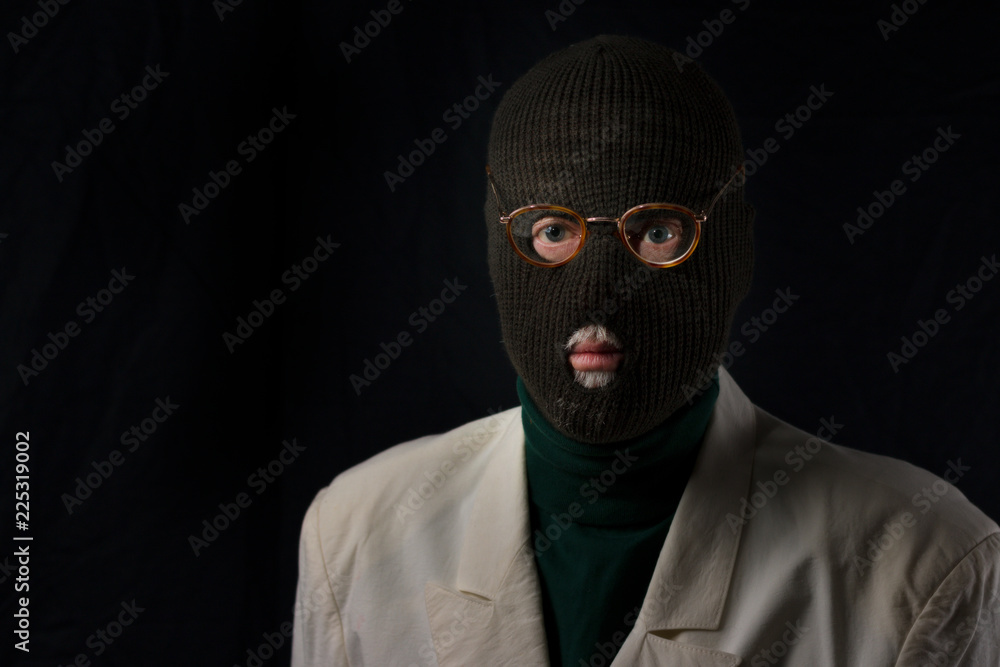portrait of senior retired burglar wearing a ski mask on black background portrait of senior retired burglar wearing a ski mask on black background