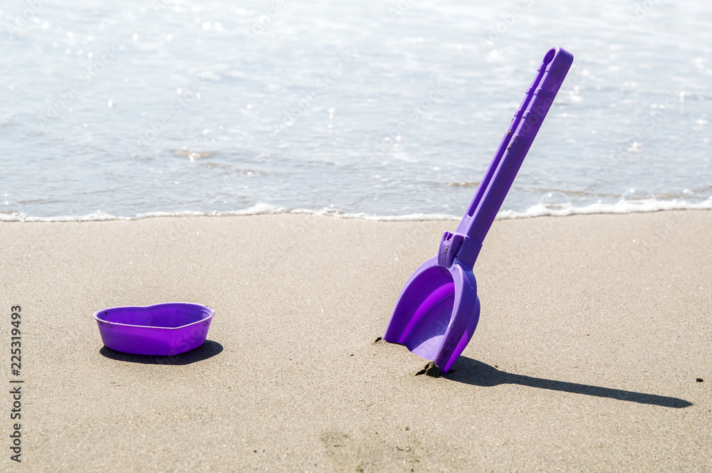 Close up. Children's mold and scapula on the seashore. Azure sea against the background. Close up. Children's mold and scapula on the seashore. Azure sea against the background.