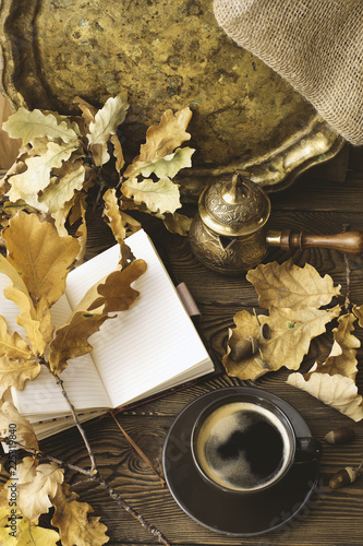 Diary, autumn oak leaves and Turkish coffee pot on a wooden background. Copy space. Cozy. Autumn concept