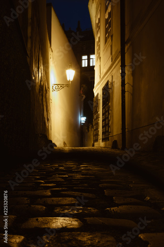 Old Prague narrow street with ancient paving stones road twilight image in Czech Republic