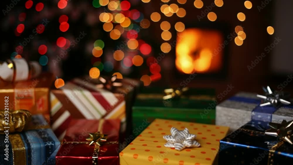 Many christmas gifts in front of fireplace and blurry lights on xmas tree in the evening - static camera, closeup Many christmas gifts in front of fireplace and blurry lights on xmas tree in the evening - static camera, closeup