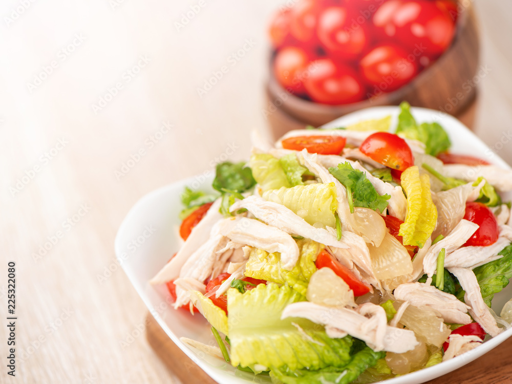 Fresh and delicious homemade chicken salad with tomatoes and pomelos in wooden background, concept of healthy and diet, top view, copy space