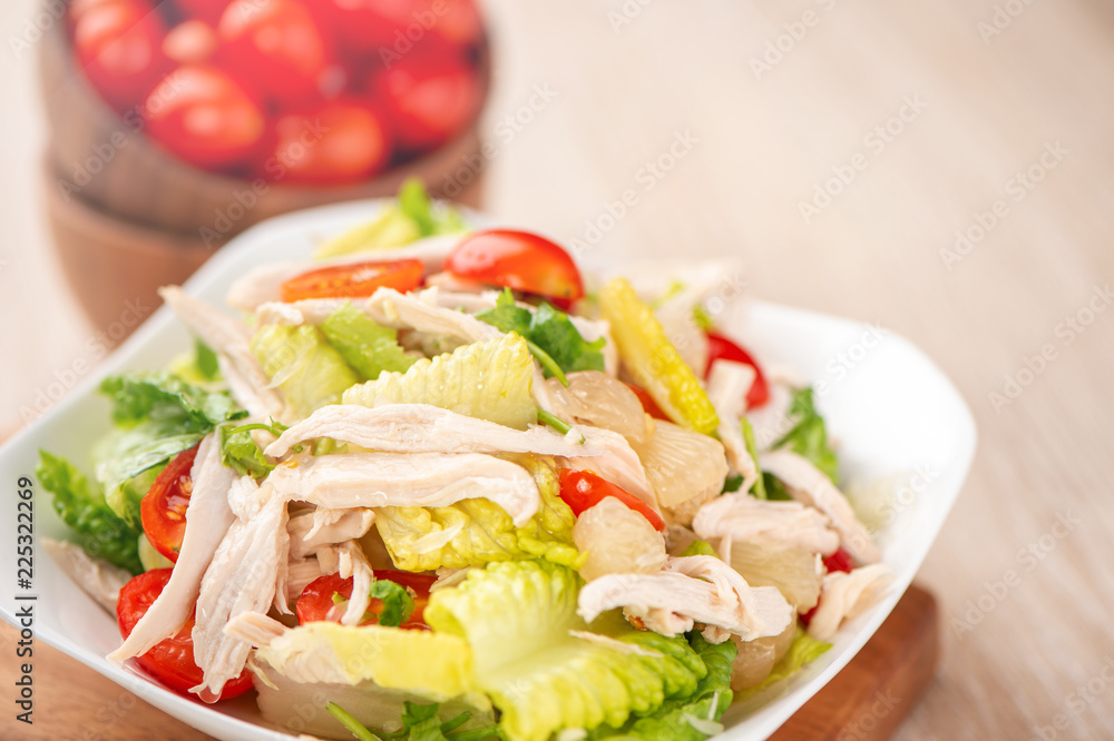 Fresh and delicious homemade chicken salad with tomatoes and pomelos in wooden background, concept of healthy and diet, top view, copy space Fresh and delicious homemade chicken salad with tomatoes and pomelos in wooden background, concept of healthy and diet, top view, copy space