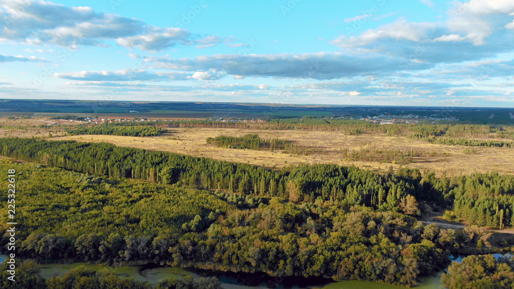 Naklejka premium Flight in the beautiful countryside among a river of woods and fields near the city