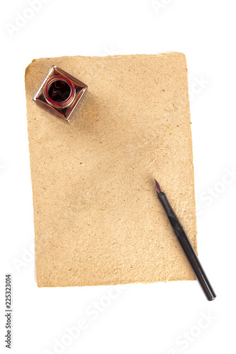 An overhead photo of an ink well with brown craft paper and an ink pen, shot from above on a white background with copy space photo