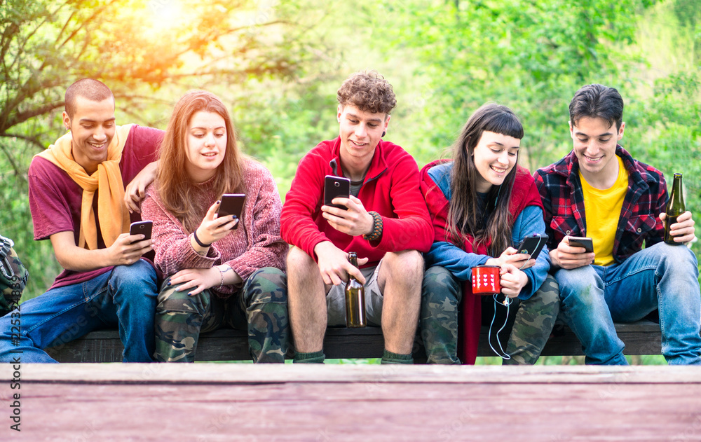 Group of young friends in a row holding mobile phone looking down