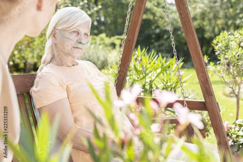 Weak elderly woman during treatment in the hospital's garden during summer