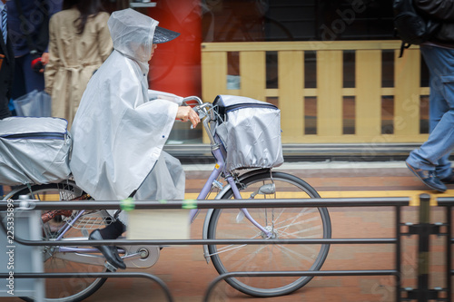 Young Japanese cyclist go to work in the rainy season in the city 