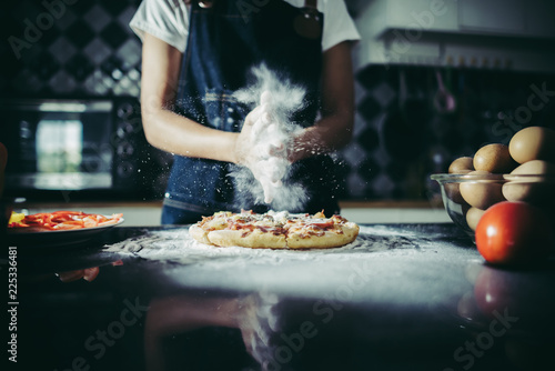 Hands in flour on black background. Making pizza in kitchen.