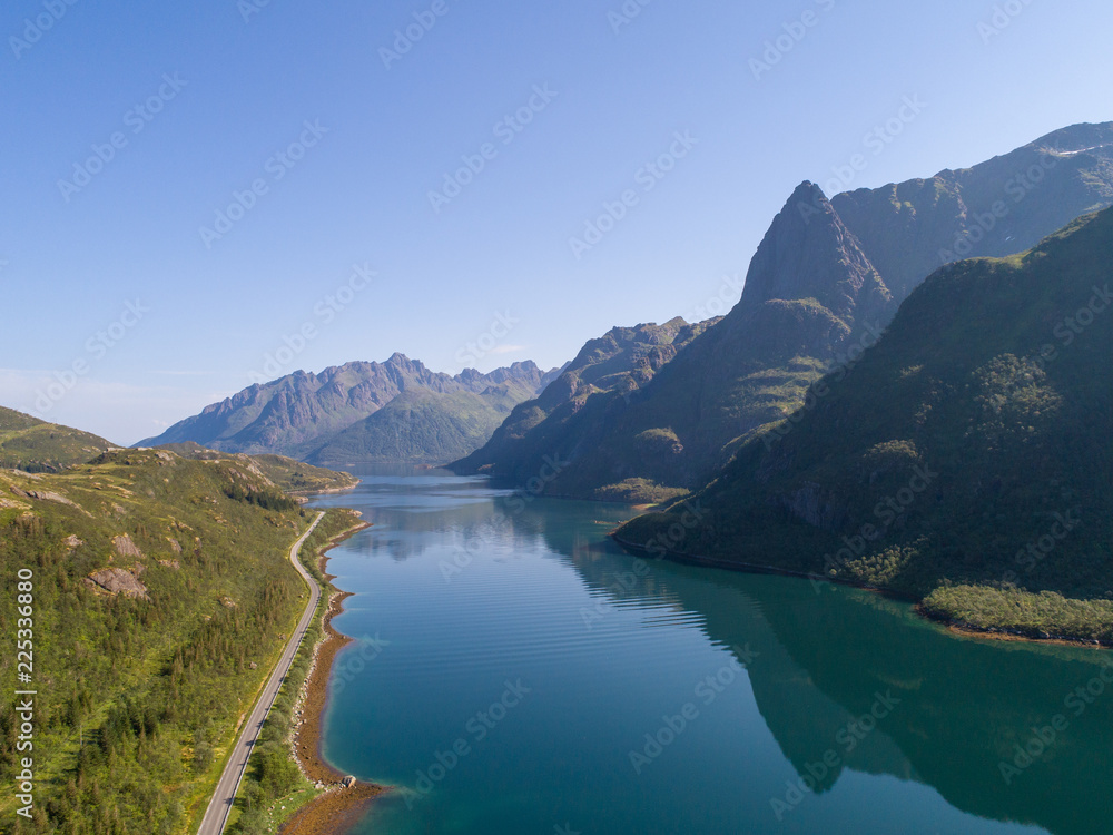 Aerial view of a road by a fjord with mountains on sunny summer day