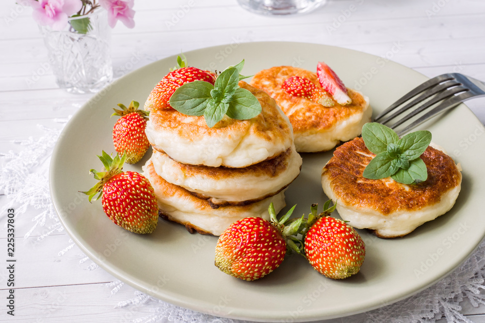 Curd pancakes with strawberries and mint on a plate Curd pancakes with strawberries and mint on a plate