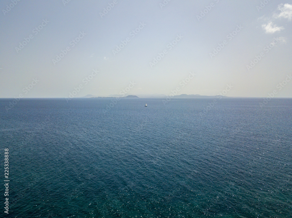Vista aerea dell’isola di Lobos, Fuerteventura. Oceano e isole viste dalle coste di Papagayo, Lanzarote, Spagna, Canarie. Barca a vela che attraversa l’oceano all’orizzonte Vista aerea dell’isola di Lobos, Fuerteventura. Oceano e isole viste dalle coste di Papagayo, Lanzarote, Spagna, Canarie. Barca a vela che attraversa l’oceano all’orizzonte