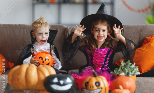 happy children in costumes of witch and vampire are preparing home for Halloween
