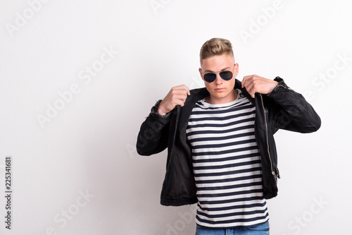 A confident young man with sunglasses in a studio, wearing striped T-shirt.