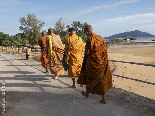 Monaci buddisti passeggiano lungo il mare photo