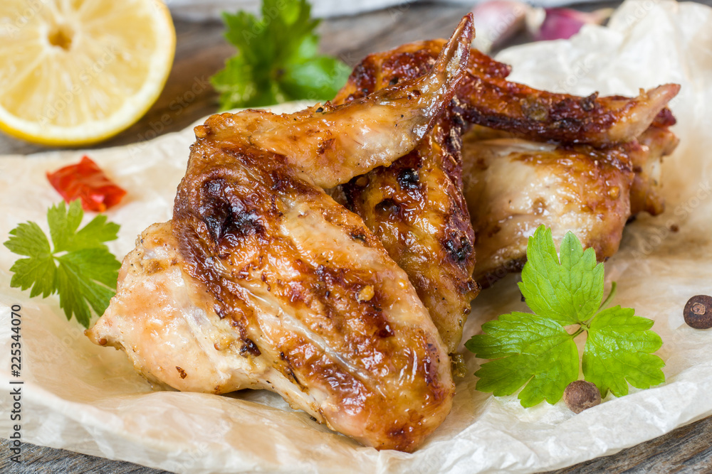 Chicken wings baked on grill with fresh herbs, lemon on wooden background. Chicken wings baked on grill with fresh herbs, lemon on wooden background.