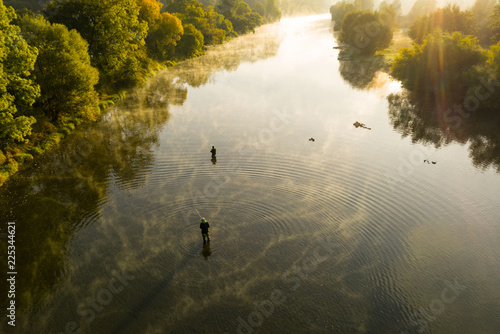 Foto Aerial shot of a man fly fishing in a river during summer morning