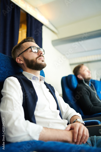 Side view portrait of handsome bearded man sleeping while enjoying first class flight sitting in comfortable seat of modern plane, copy space