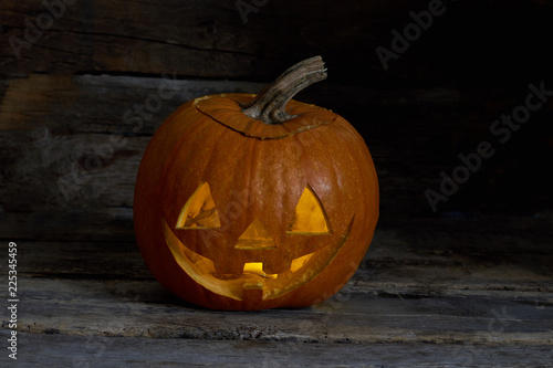 Halloween pumpkin head on wooden background. Carved Jack O Lantern. Symbol of Halloween holiday.