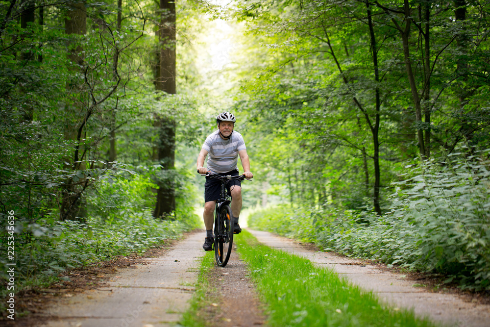 Senior man biking in forest, enjoying healthy active lifestyle outdoors in summer