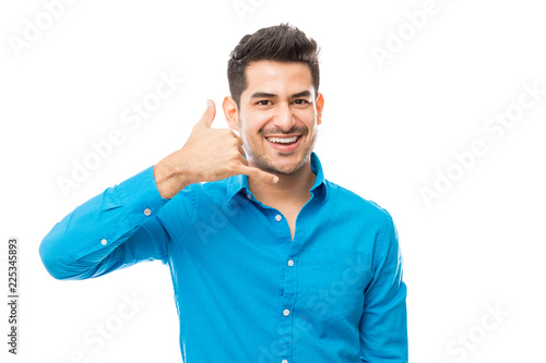 Smiling Man Showing Call Me Gesture On White Background © AntonioDiaz