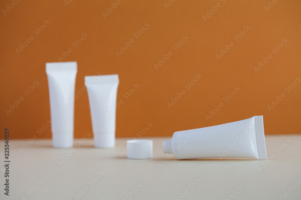 Fototapeta premium Hygiene cosmetic tubes on brown and beige background. Blank white opened plastic container, simple packaging design. shallow depth of field, copy space photography.