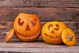Two Halloween pumpkins on wooden background. Scary and funny pumpkins carved for Halloween party.