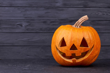Halloween pumpkin with happy expression. Halloween pumpkin head with smile on black background, copy space. Halloween carving ideas. Halloween greeting card.
