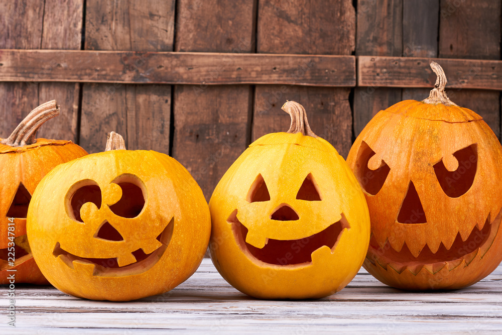Obraz premium Halloween holiday pumpkins on wooden background. Orange autumn pumpkin Halloween holiday gourd jack o lantern faces.