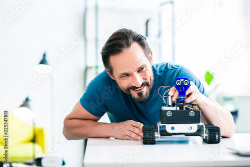Delighted bearded man using his robotic device at home