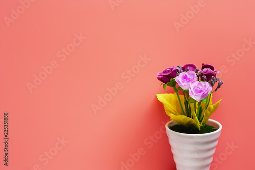 Artificial pink and purple rose bouquet in white flower pot on pink background for love and Valentine s day concept