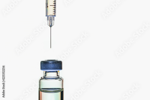 A syringe with the needle point to the vaccine vial on the white background photo
