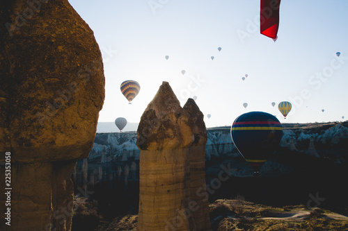 Goreme, Turkey - April 4, 2012: Hot air balloons for tourists flying over rock formations at sunrise in the valley of Cappadocia. photo