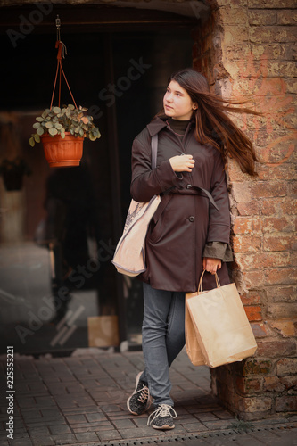 teenager girl with long brown hair street photo with shoping bag on city windowshop background photo