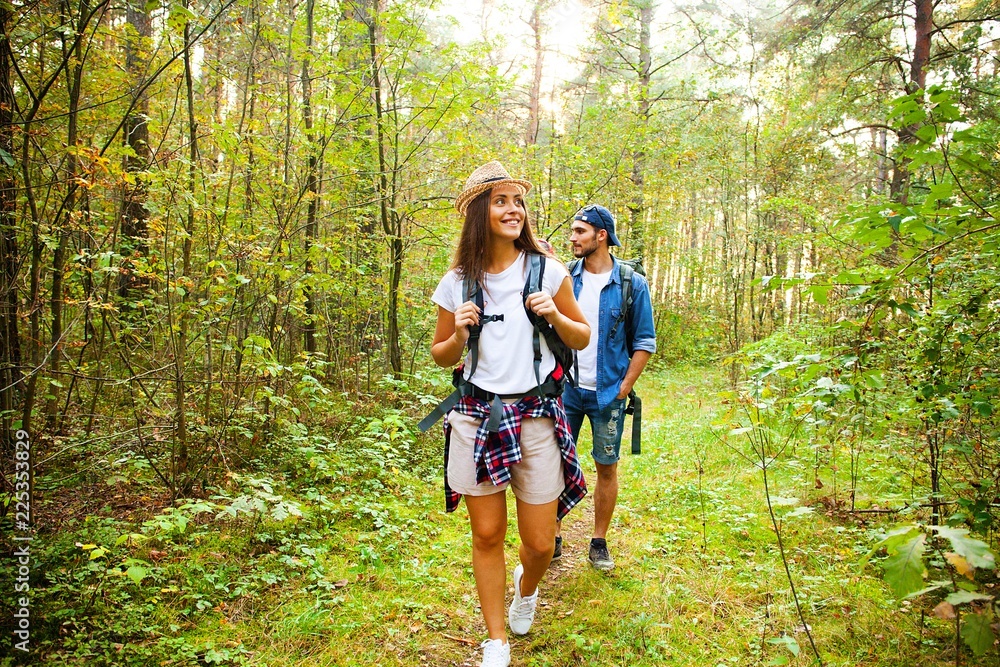 Tough route. Beautiful young couple hiking together in the woods while enjoying their journey. Tough route. Beautiful young couple hiking together in the woods while enjoying their journey.