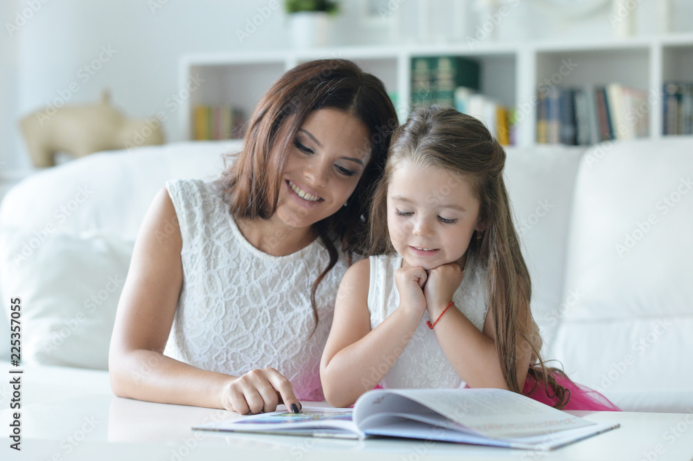 little cute girl reading book with mother at the table little cute girl reading book with mother at the table