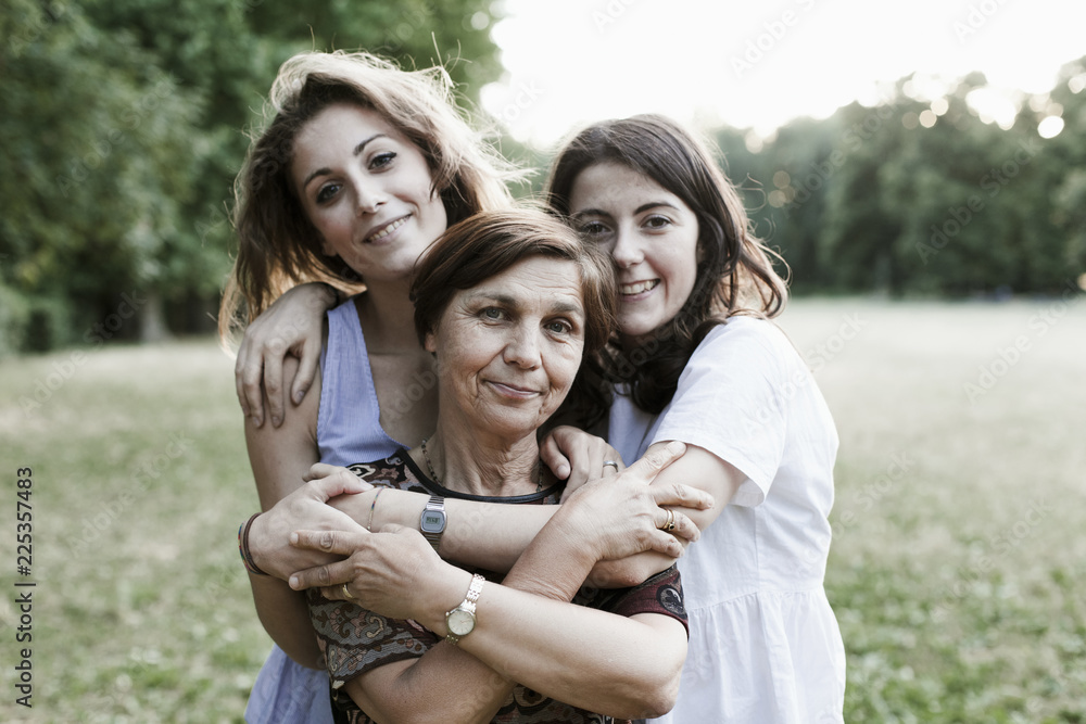 Mother and daughters embrace in a park at sunset on a summer evening Mother and daughters embrace in a park at sunset on a summer evening