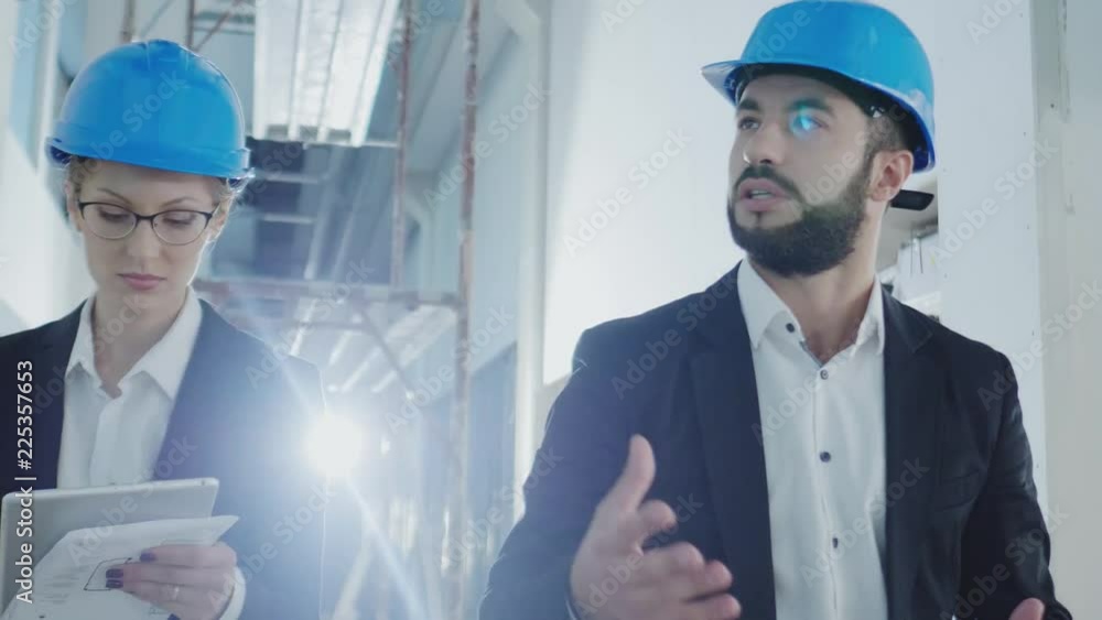 Engineers in hardhats have conversation in a factory Engineers in hardhats have conversation in a factory