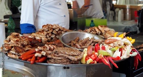 Large heated tray with the traditional street serbian food. The typical grilled meats . like cevapi, sausages, pljeskavica and  chicken, together with vegetables photo