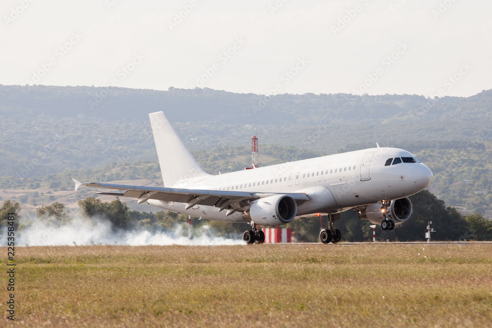 White passenger plane is landing on the airport. Touchdown with tire smoke White passenger plane is landing on the airport. Touchdown with tire smoke