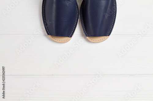Summer blue sandals with white sole on white woooden background. Top view, place for text, copyspace.