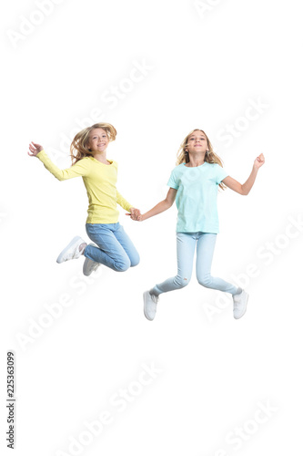 Cute girls in casual clothing jumping on white background